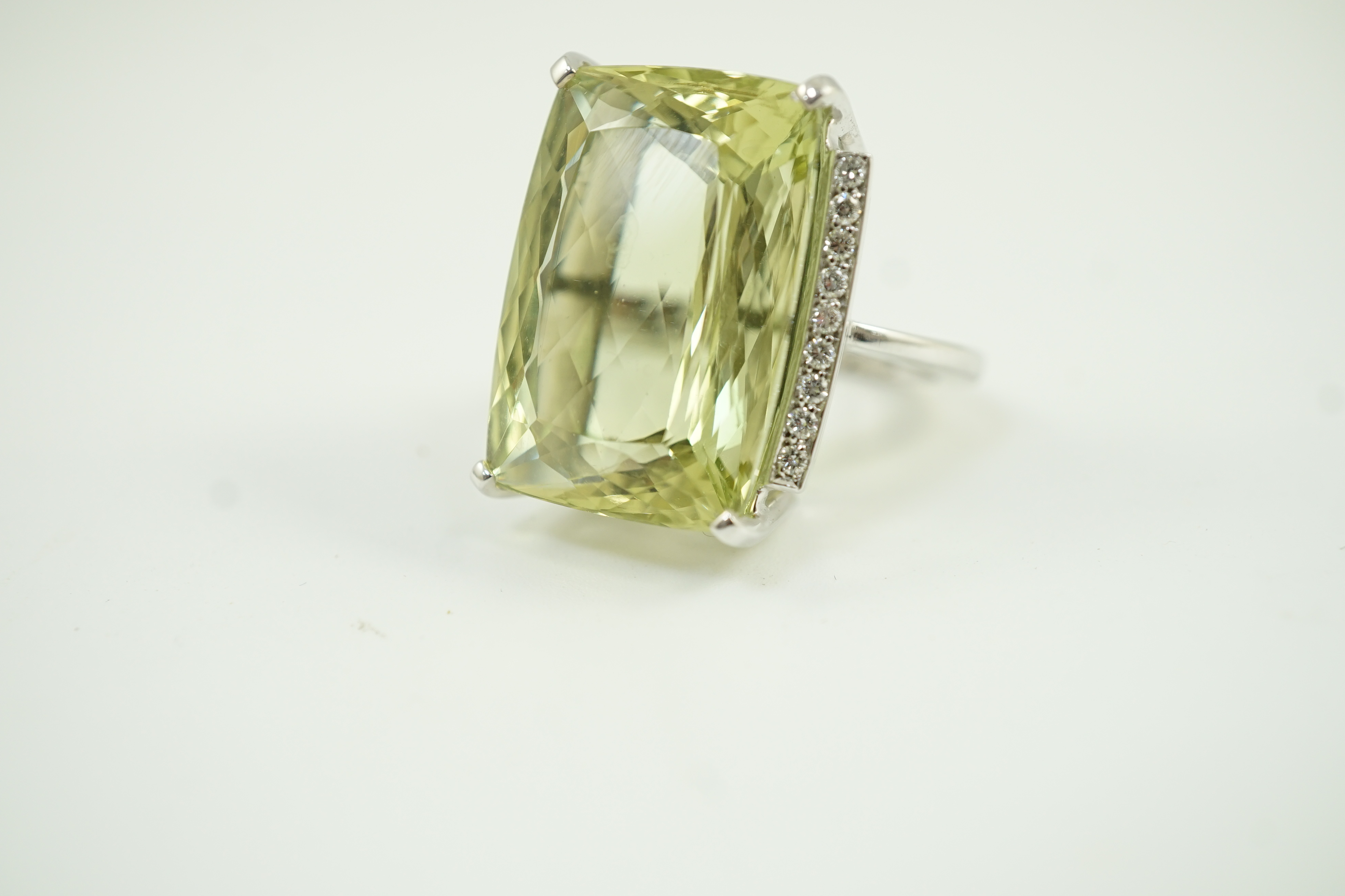 A modern white gold and shaped rectangular fancy cut pale green beryl set dress ring, with diamond chip setting